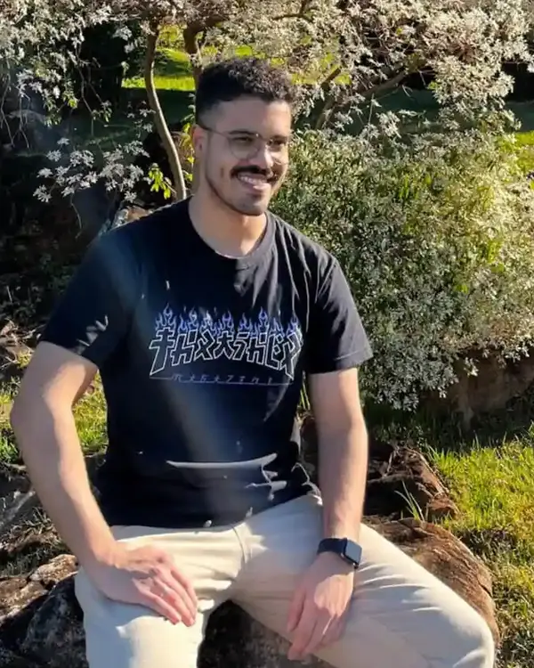 Pedro Satin, sentado em uma pedra em um parque